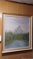 Full framed painting of a mountain scene showing the mountain, forest and lake with light blue-gray sky.