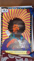 Full view of vintage Jimi Hendrix psychedelic poster with vibrant yellow and pink spiral background, showing tears and wear.