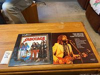 Photo of Black Sabbath 'Sabotage' vinyl record album cover with band photo, sitting on a wooden table.