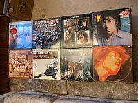 Full view of all 8 vinyl record covers laid out on carpet.