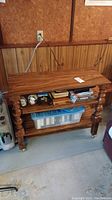 Full view of wooden rolling shelf with three tiers, turned legs, casters, and some minor wear.