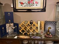 Photo of assorted barware on table including wooden wine racks with bottles, decorative trays, empty bottles, and Johnnie Walker Blue Label King George V items