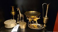 Photo showing full assortment of brass decor including vases, giraffe figurines, bowls, trays, and lidded containers