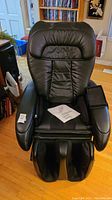 Front view of black Panasonic massage lounger showing headrest, armrests, seat and foot massager