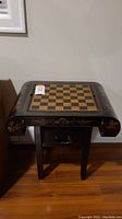 Front view of table showing chess board on top with curved sides and gold motif