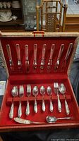 Full flatware set arranged inside a red velvet-lined case showing all pieces in place.