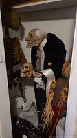 Rear-corner view of full skeleton and butler figures standing together