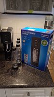 SodaStream Source sparkling water maker with four bottles and original box displayed on kitchen counter.