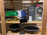 Shelf items including green glass banker's lamp with brass fittings, black tape recorder, small gray and green metal drawers organizers, and a computer monitor visible in background.