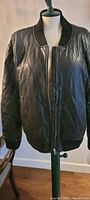 Black Wilfred Free quilted bomber jacket on a dress form with ribbed collar and cuffs.