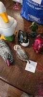 Overview of various duck figurines including ceramic and wood pieces on a wooden table.
