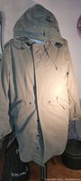 Full front view of beige/military green TNA cold weather parka with hood extended.