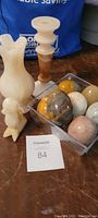 Lot showing all alabaster items including eggs in container, candle holders, and duck figurine on table