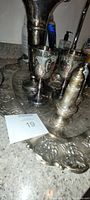 Photo showing two EPNS goblets, silver salt shaker, and part of embossed silver tray