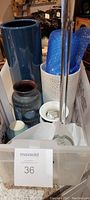 A view of multiple ceramic vases in varying sizes and colors including blue and textured white, with bubble wrap and candle holder, inside a container
