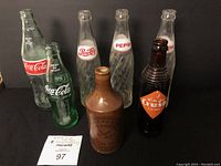 Full view of all seven bottles showing Coca-Cola, Pepsi, Orange Crush, and Bird Ginger Beer bottles together