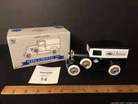 Black and white Ford Model A toy bank with original box, showing full vehicle and packaging