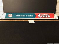 Full view of the push bar sign with Orange Crush advertising text and logos.