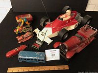 Photo showing entire lot of 8 vintage toy vehicles including large race car, vintage fire truck, bus, motorcycles, and other toy cars all in used condition.