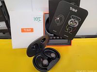 Top view showing black Tribit MoveBuds H1 sport wireless earbuds seated in open charging case, accompanied by original box, user manual, and extra ear tips.