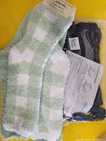 Photo of Aeropostale green and white checkered fuzzy socks with black pair of socks in original packaging, includes instruction sheet visible.