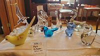 Collection of art glass birds including swans, pelican, ducks, and small birds in various glass colors on table.