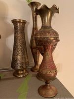 Four brass vases arranged together highlighting varied shapes and detailed etching and painting