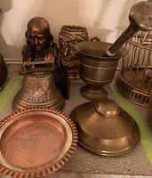 Antique French brass bell, brass mortar and pestle, copper finish Ben Franklin bank, heavy brass-faced mug, and brass ink well all displayed together showing condition and style.