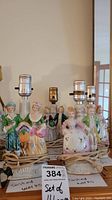 Four vintage ceramic figurine lamps with attached cords and light sockets, arranged in a row.
