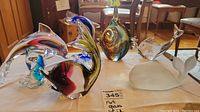 Overall photo showing seven different art glass marine life sculptures on a table, with visible details of colors and shapes