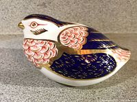 Side view of Royal Crown Derby quail figurine showing rich cobalt blue and red feather details with gold accents.