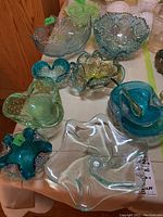 Various blue-green and clear glass bowls arranged together showing shapes from star to abstract with ruffled edges and gold fleck details.