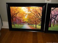 Full view of framed wall art depicting a path lined with trees in autumn colors of orange and yellow leaves.