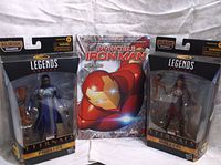 Two Marvel Legends Series Eternals action figures and one hardcover Invincible Iron Man comic book.
