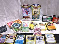 Full view of the lot showing loose cards sorted in piles, unopened Energy Packs and booster packs, and several individual cards laid out including Trainer and Pokemon cards