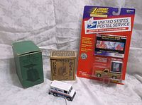 Photo showing USPS collectible toys: white USPS mail truck toy, yellow Johnny Lightning USPS truck toy and Space Fantasy Series stamp collection card.