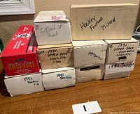 Nine cardboard boxes labeled by brand and year on tabletop