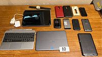Overview photo of electronic devices on wooden surface including laptops, tablets, phones, chargers, and cases