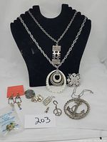 Full view of all jewelry on black necklace display showing necklaces, pins, earrings, and pendants.