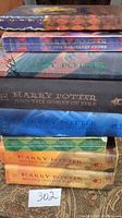 Stack of 7 Harry Potter books showing spines and covers, mixture of hardcover and softcover editions.