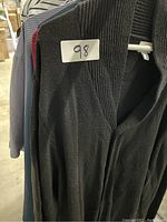 Black knit zipper cardigan with ribbed collar on hanger labeled 98