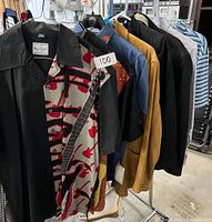 Photo of six men's button-up shirts hanging on a rack, including a black shirt with a red guitar graphic.