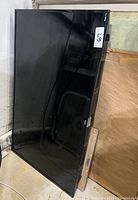 Full view of the TV lying flat against a wall with a reflective screen showing surrounding items.