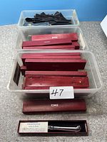 Multiple Towle letter openers in maroon boxes stacked in plastic bins.