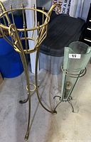 Metal and glass plant stands in a storage or workshop area showing overall structure of each stand.