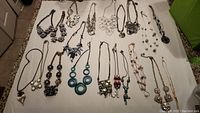 All 20 necklaces laid out on white surface for overall display.