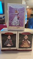 Front view of three unopened Hallmark Barbie keepsake ornaments in original boxes, showing the Springtime Barbie and two Holiday Barbies.