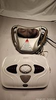 Image of three massagers: Homedics shiatsu kneading massager on top, Homedics white vibration foot massager below, and HealthFocus eye massager with black and white casing.