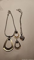 Photo of Brighton jewelry set including heart-shaped crystal necklace and matching geometric earrings and pendant on silver-tone chains.