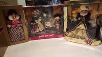 The three boxed vintage Barbie sets displayed side by side. Includes Holiday Sisters set with Barbie, Kelly, and Stacie dolls in holiday attire, and Happy Holidays Barbie in a black and gold gown with white fur accents.
